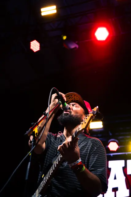 Guitarist singing under red stage lights