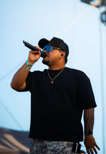 Artist in sunglasses performing on a festival stage