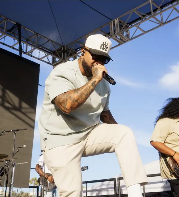Artist kneeling at the edge of the stage mid-song