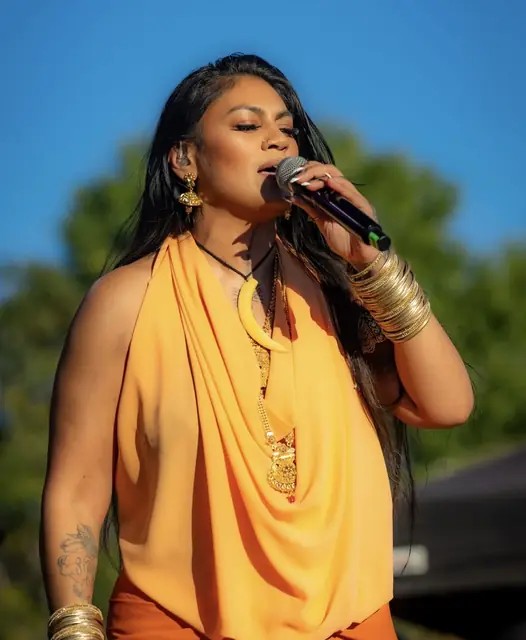 Singer in orange performing on an outdoor stage