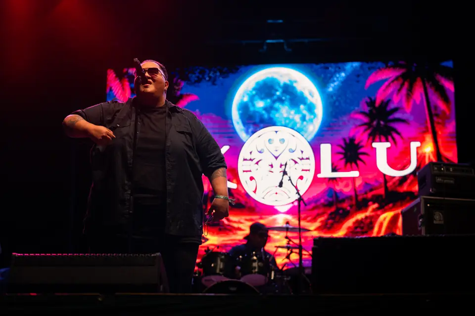 Singer on stage in front of a moon and palm tree screen