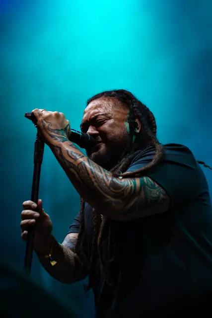 Singer gripping the mic under teal stage lights