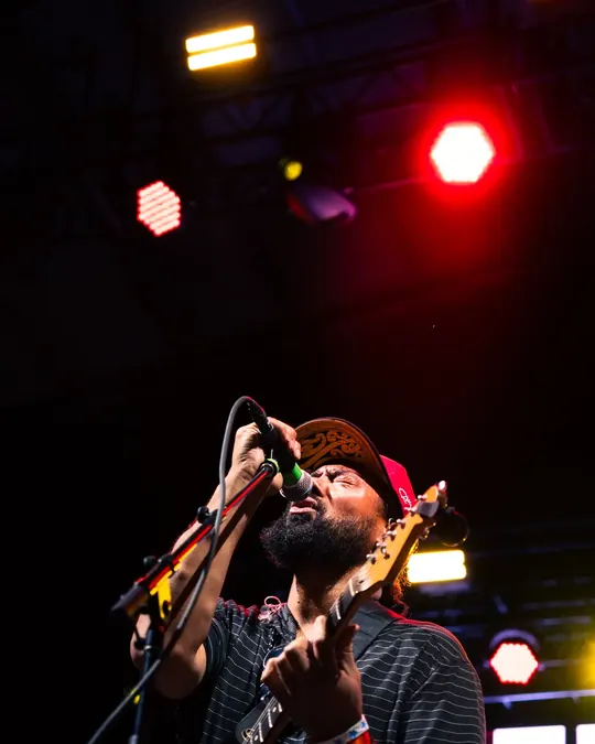 Guitarist singing under red stage lights