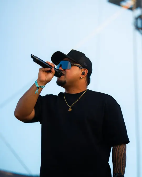 Artist in sunglasses performing on a festival stage