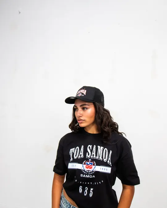Model in a Toa Samoa tee and cap looking off frame