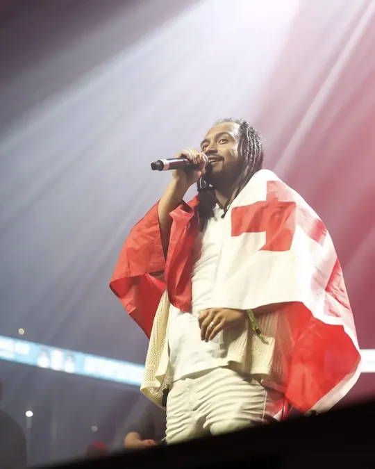 Singer draped in the Tonga flag under stage lights